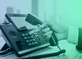 Uma mão segurando um telefone fixo e discando uma tecla.